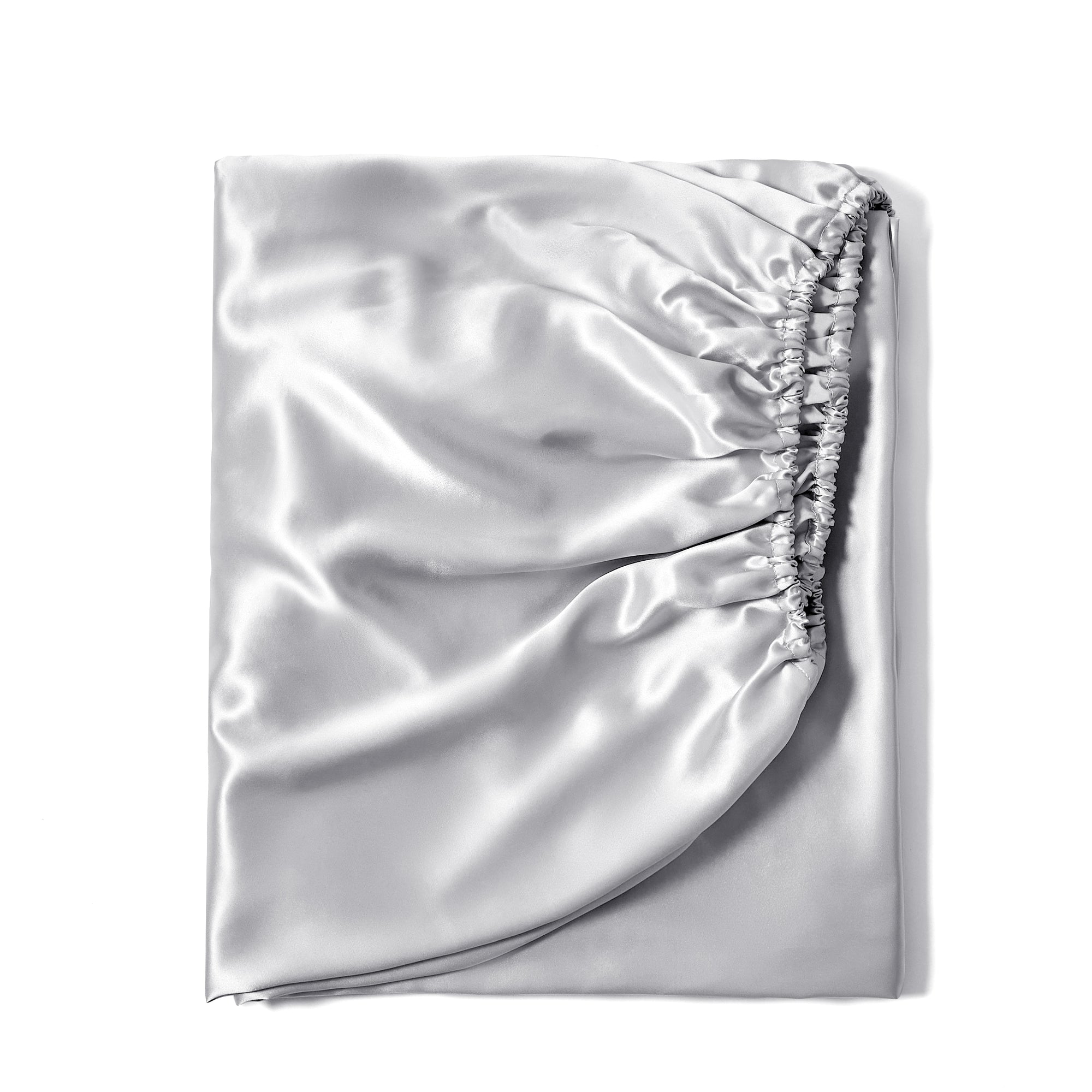 22 momme silk fitted sheet in Gunmetal on bed with upholstered headboard in a cozy bedroom setting