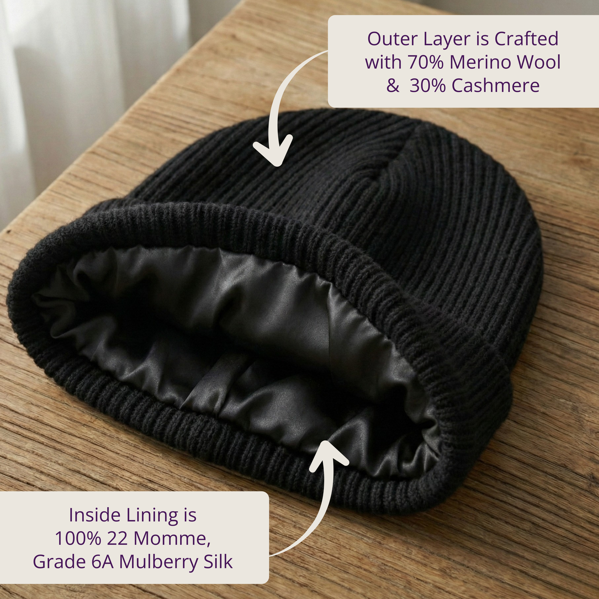 Black knitted hat with merino wool and cashmere outer layer and silk lining on a wooden surface.