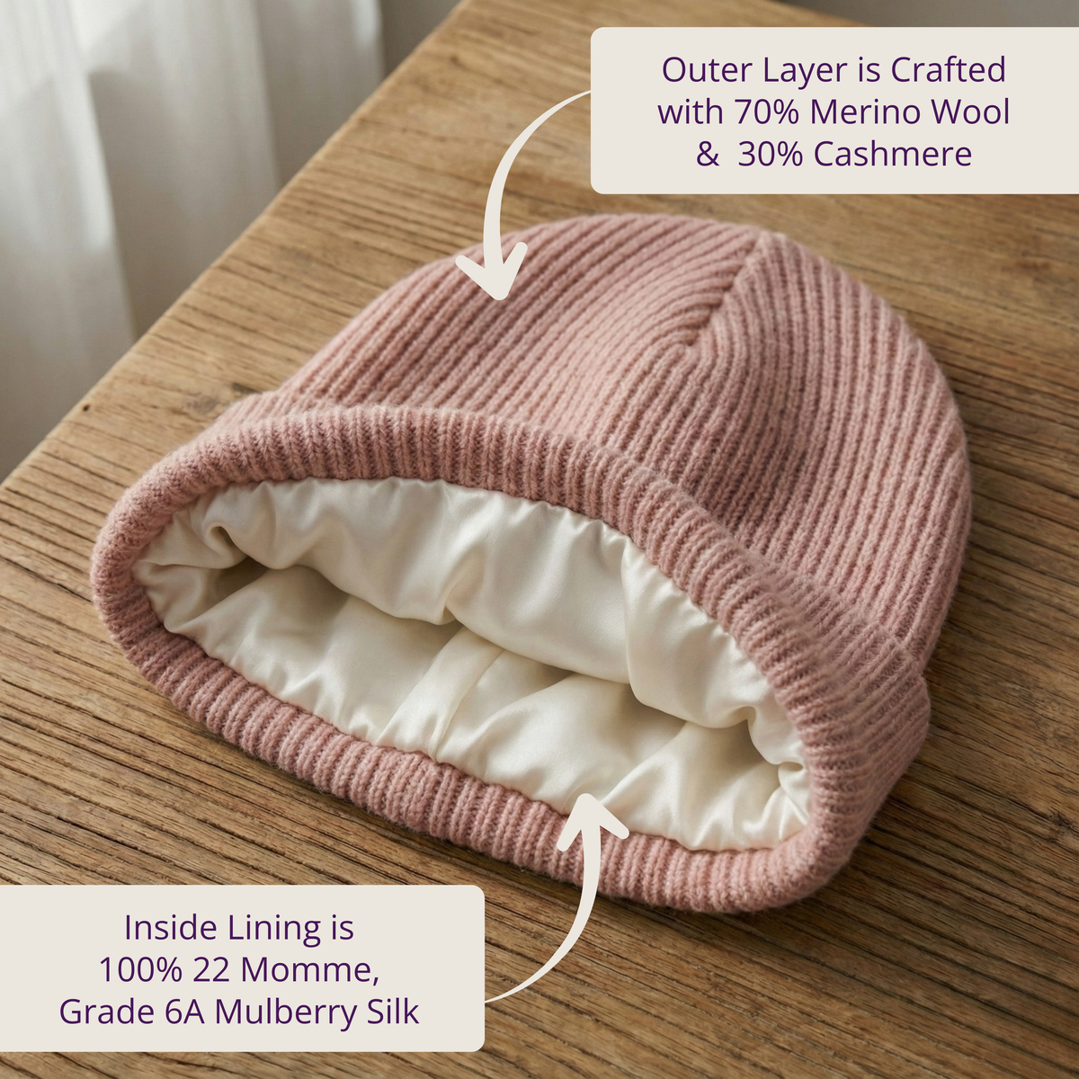 Pink knitted winter beanie with text about wool, cashmere and silk composition on a wooden surface