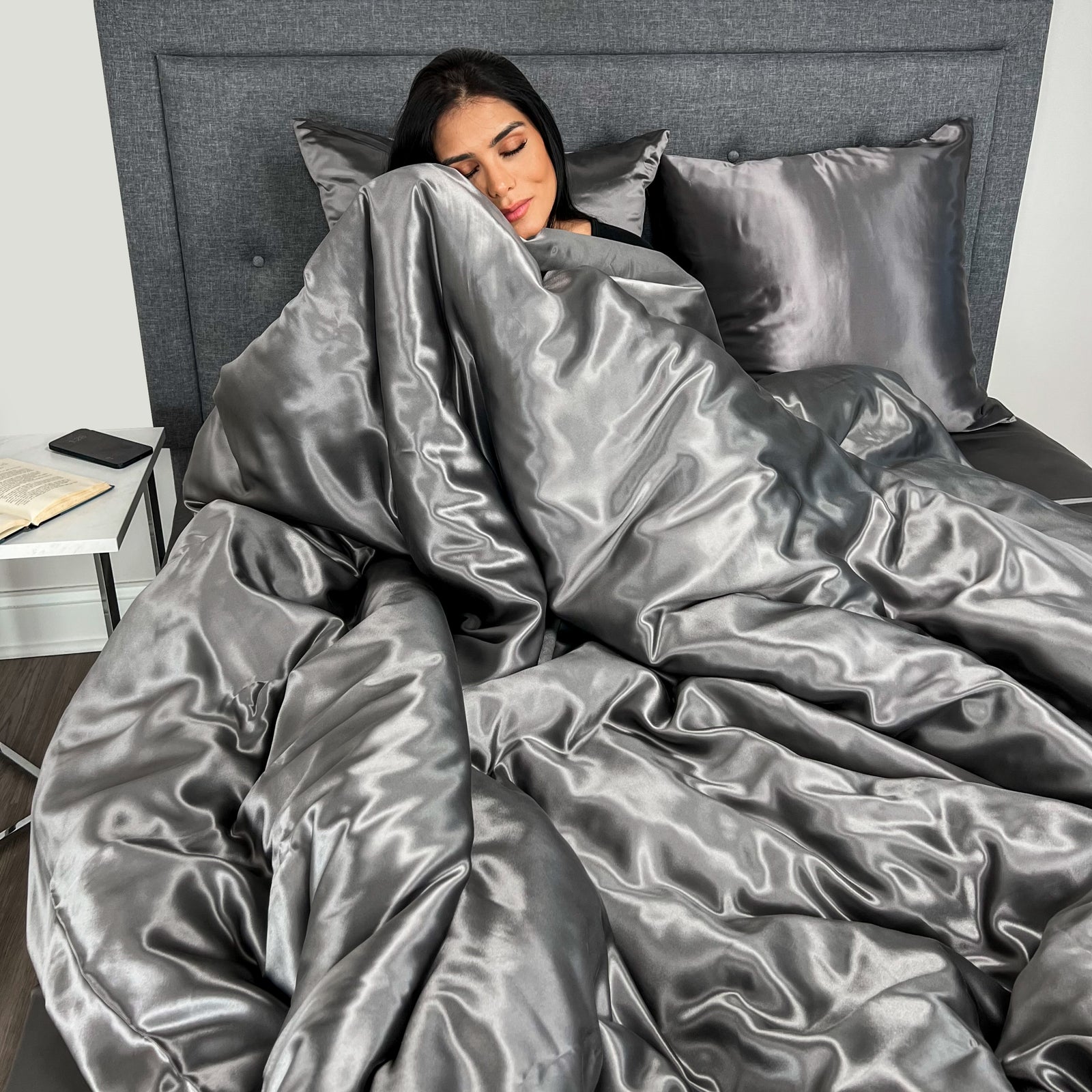 Woman enjoying comfort on a bed with a silk duvet cover, duvet insert, and matching pillowcase