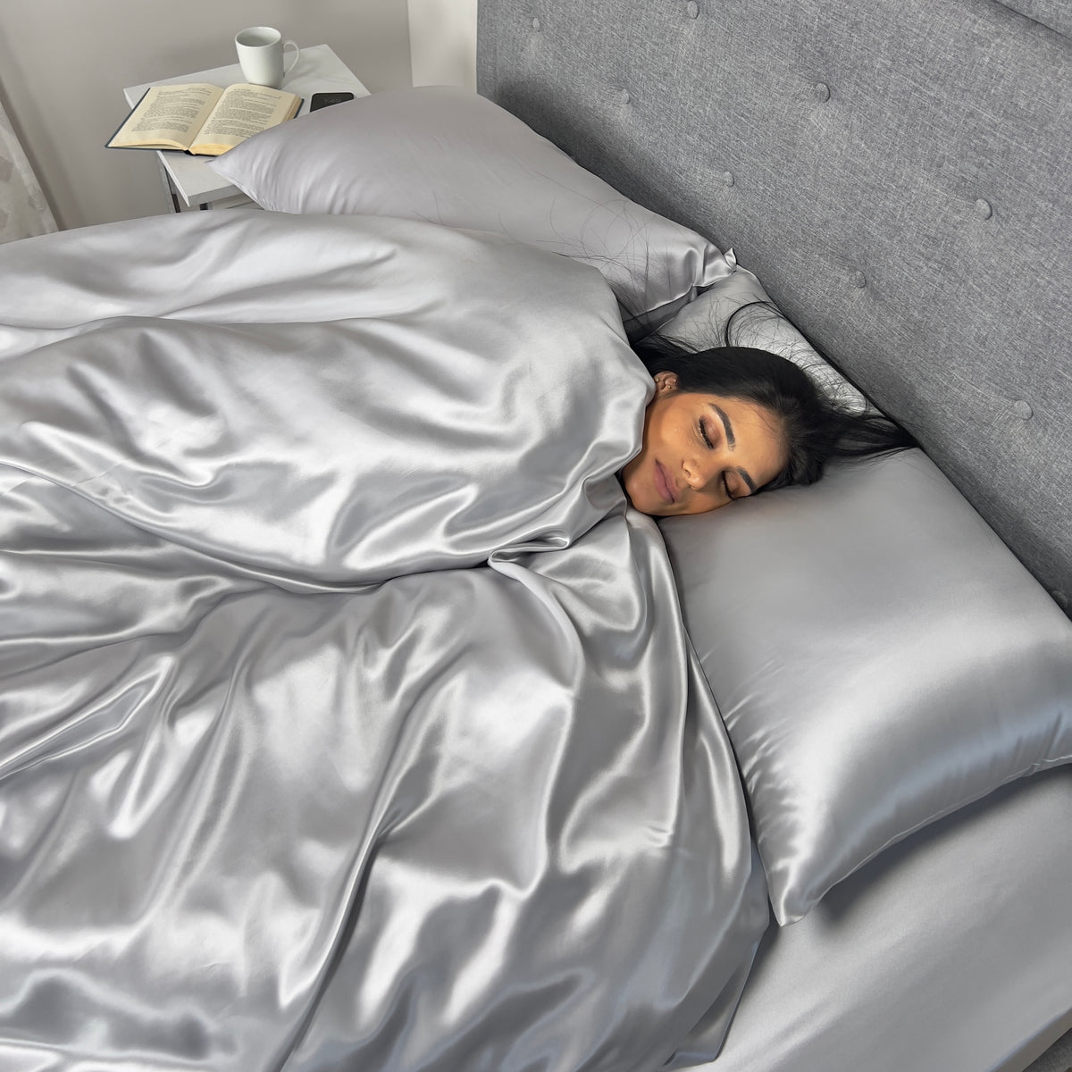 A Woman sleeping peacefully in bed, covered by a luxury soft mulberry silk duvet cover for comfort 