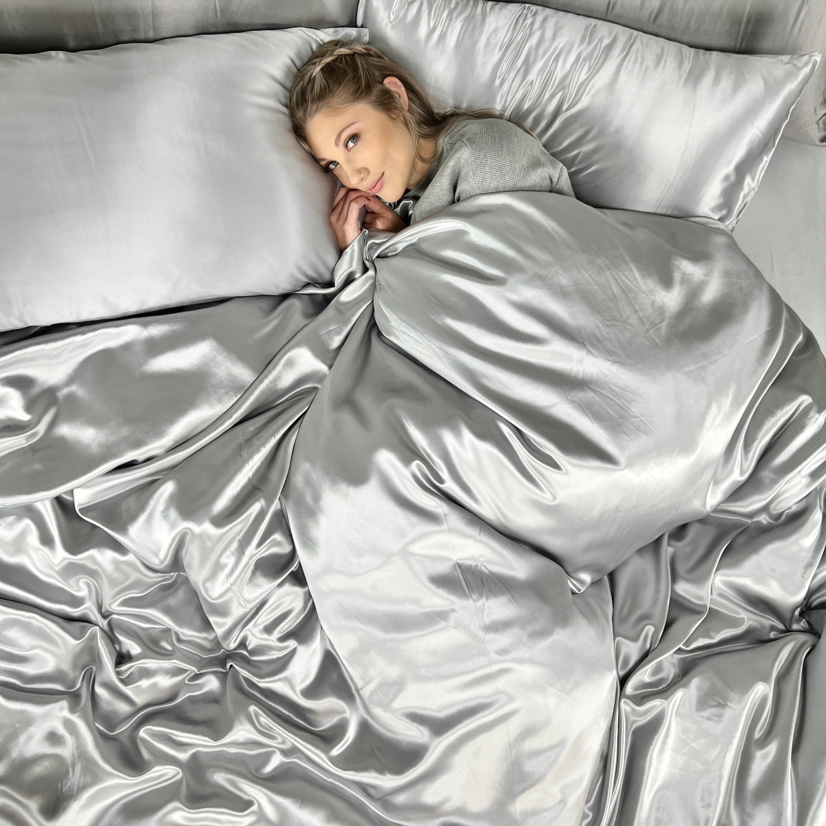 Woman enjoying comfort on a bed with a silk duvet cover, duvet insert, and matching pillowcase