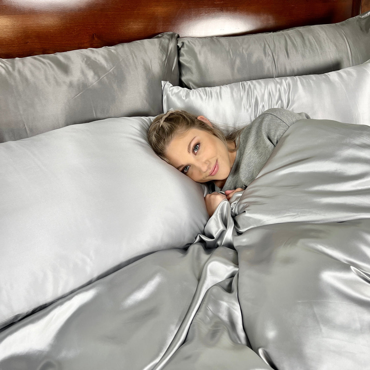 Smiling woman enjoying comfort on a bed with mulberry duvet cover and matching pillows under head
